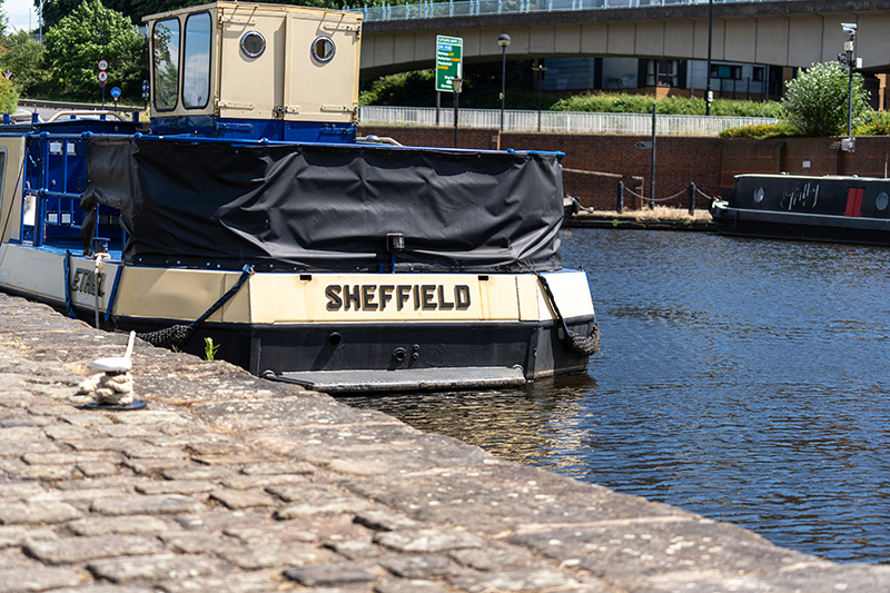 Barge in a canal. It says Sheffield on the back