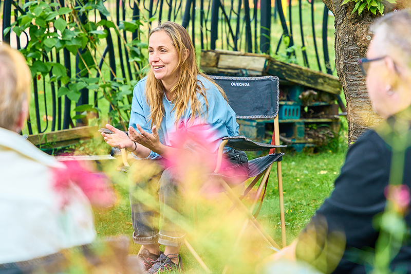 Woman sat in a camping chair outdoors, talking to others